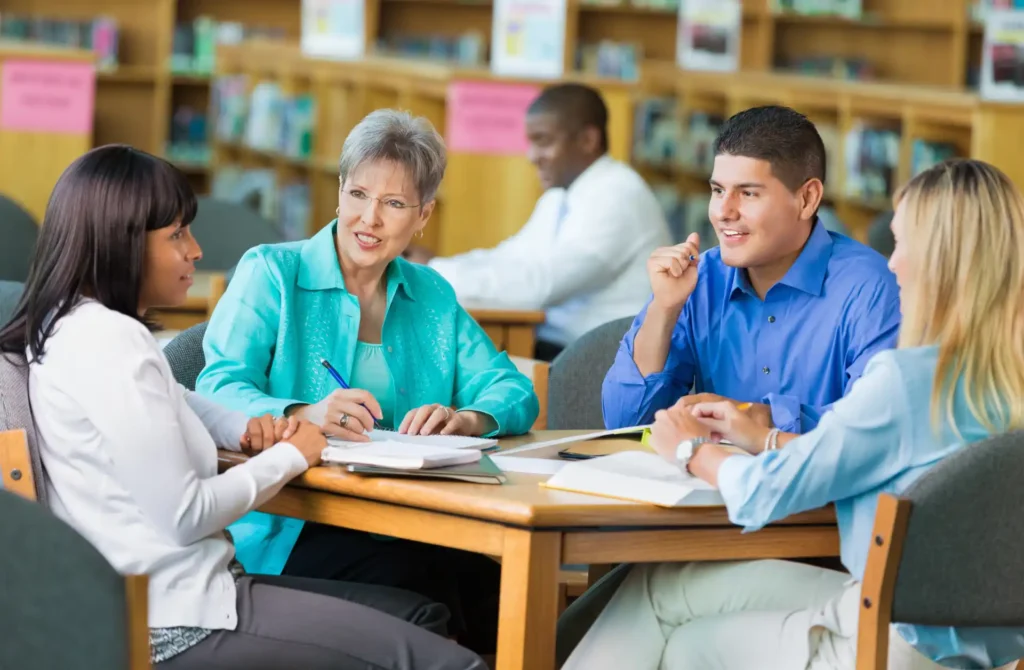 Library staff meet at a table in a common area.